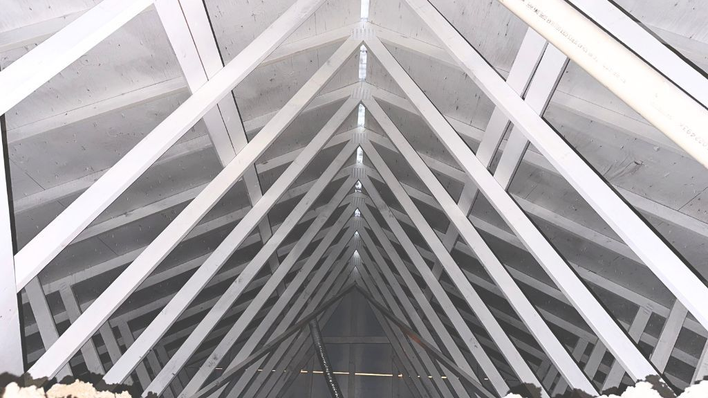Interior view of white wooden rafters forming a triangular roof structure.