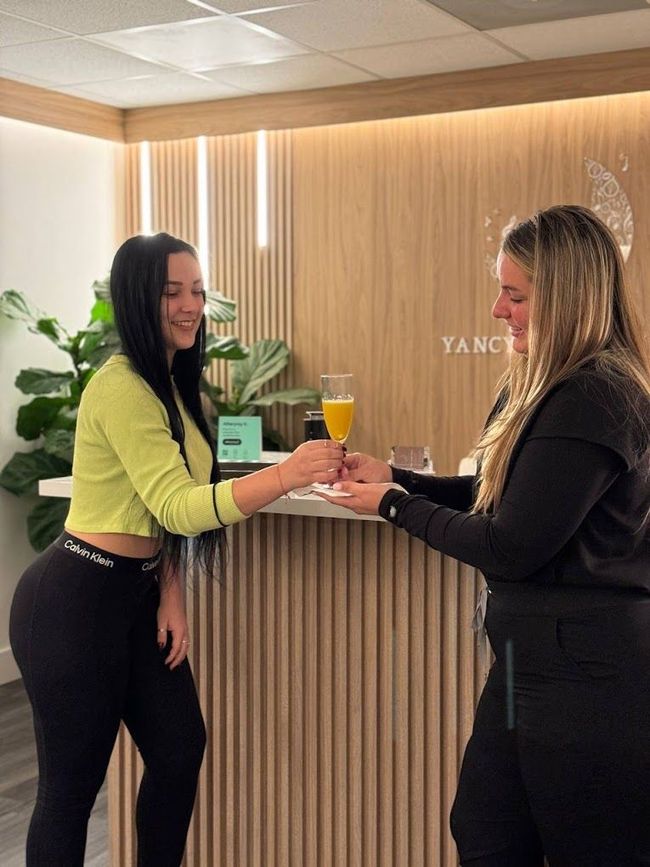 Two women are standing next to each other at a counter in a room.