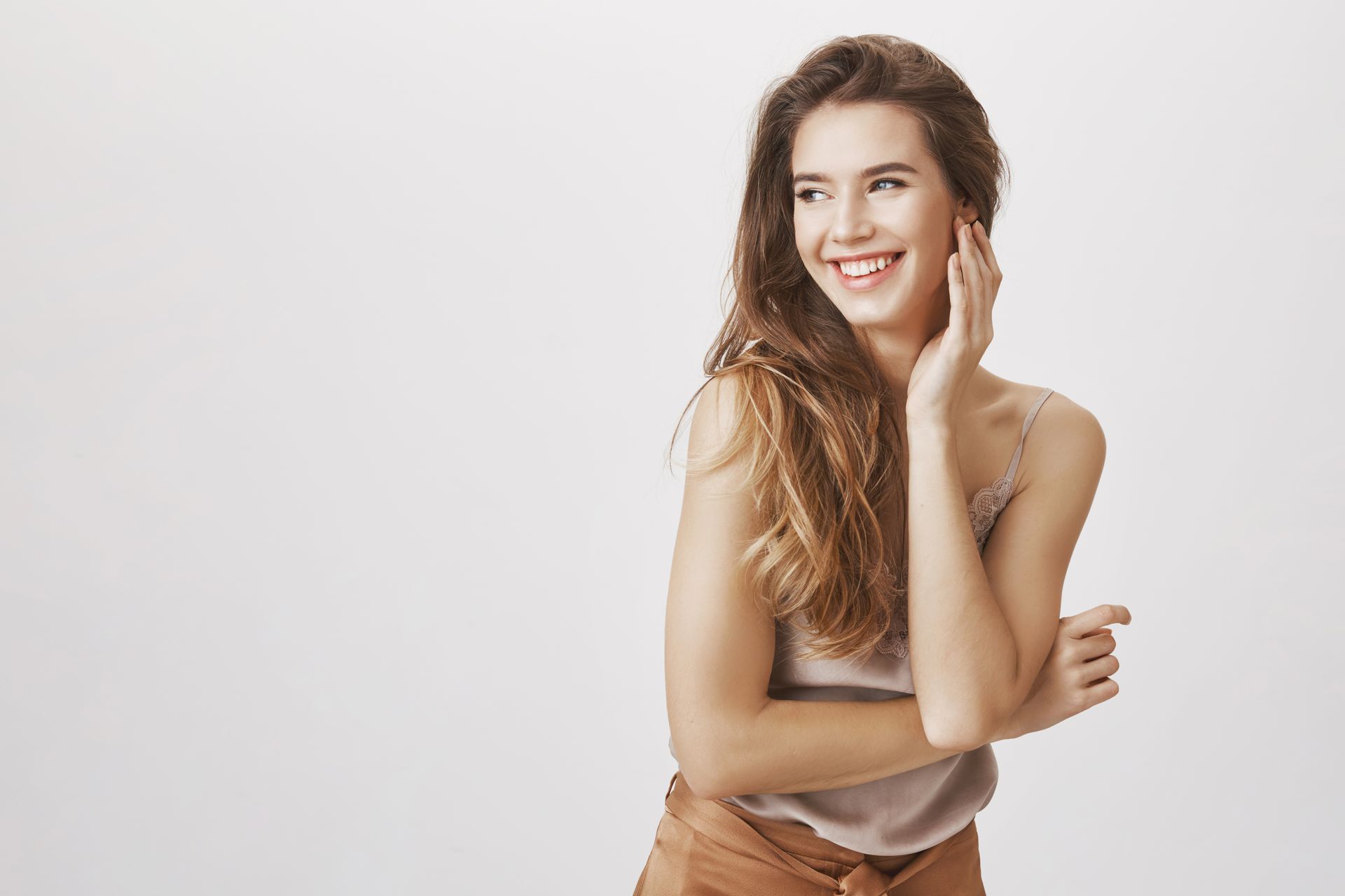 A woman is smiling and pointing at something while touching her ear.
