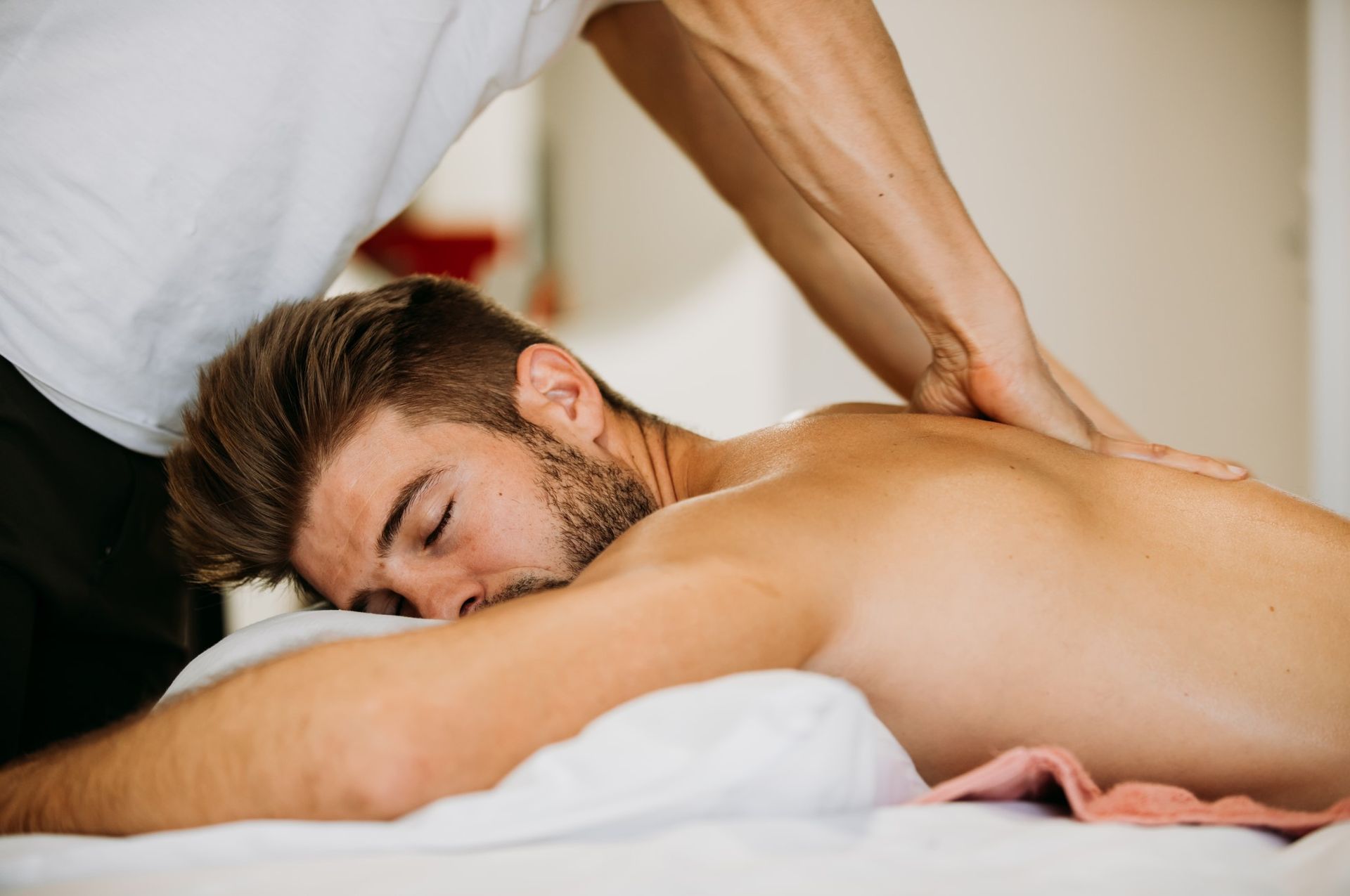 A man is laying on a bed getting a massage from a massage therapist.