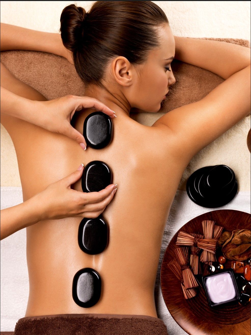 A woman is getting a massage with rocks on her back