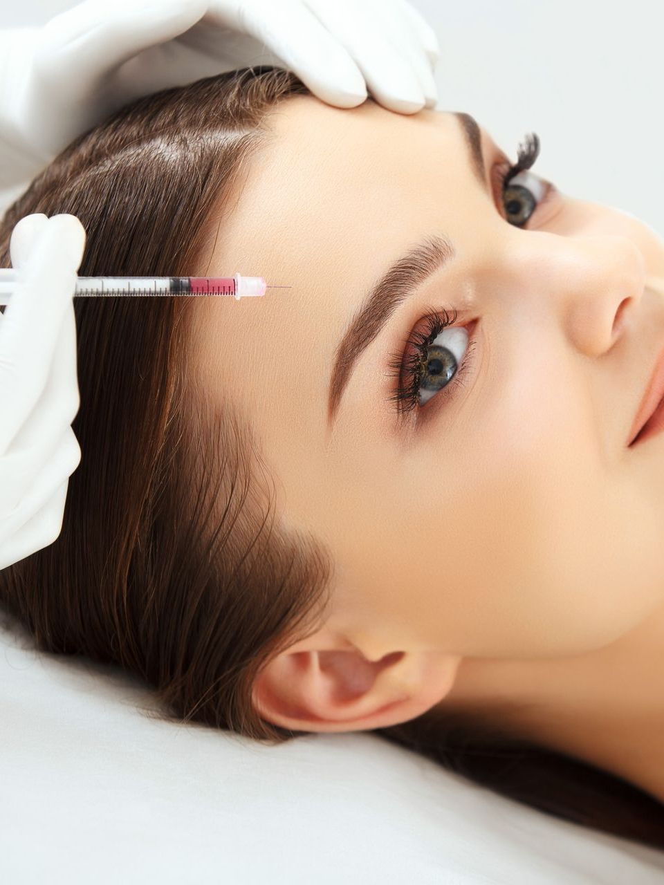 A woman is getting a botox injection on her forehead