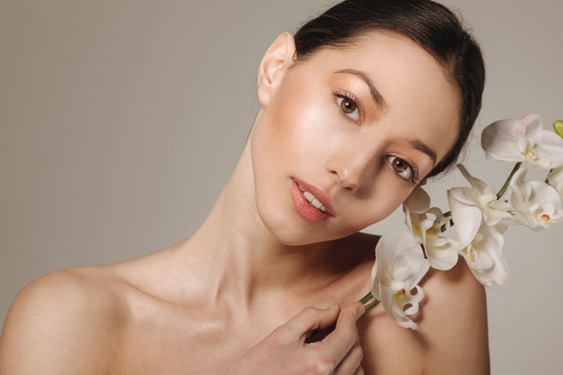 A woman is holding a white flower in front of her face.