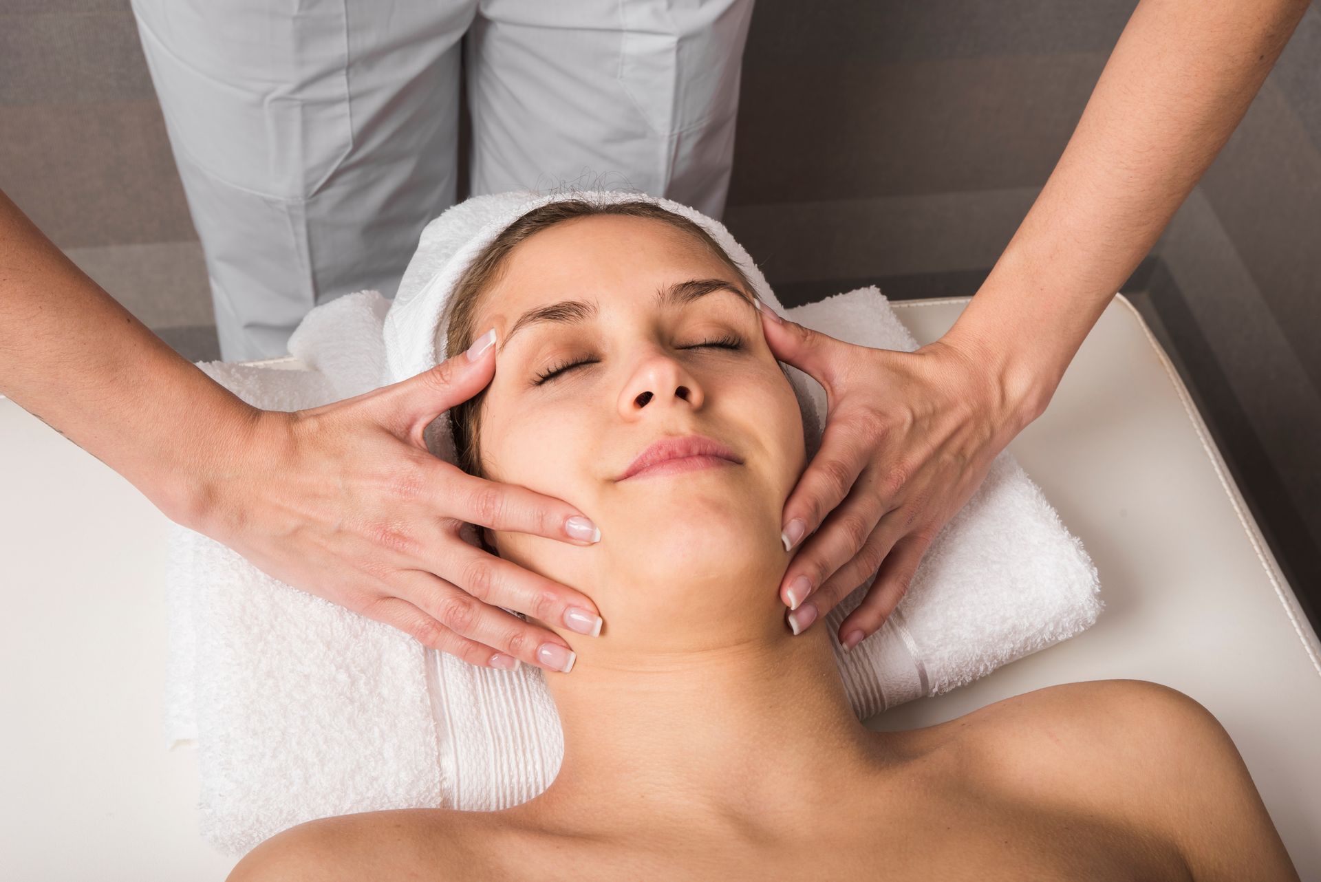 A woman is getting a facial massage in a spa.