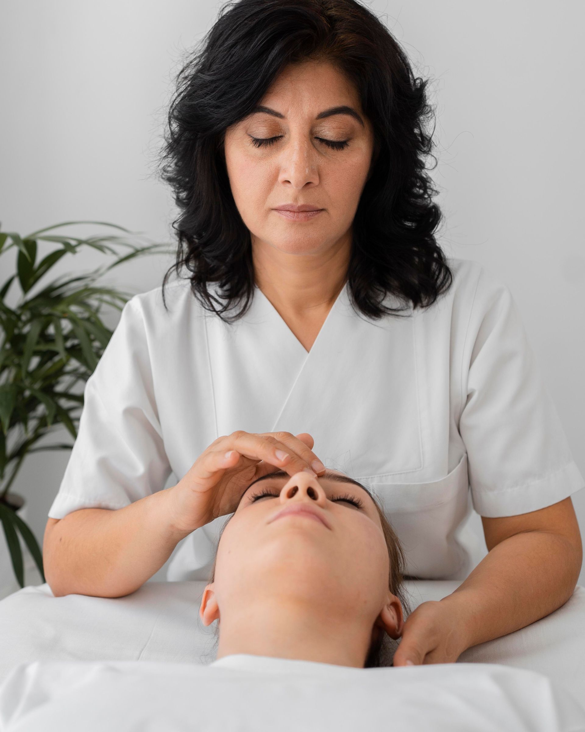 A woman is giving a woman a massage on her face.