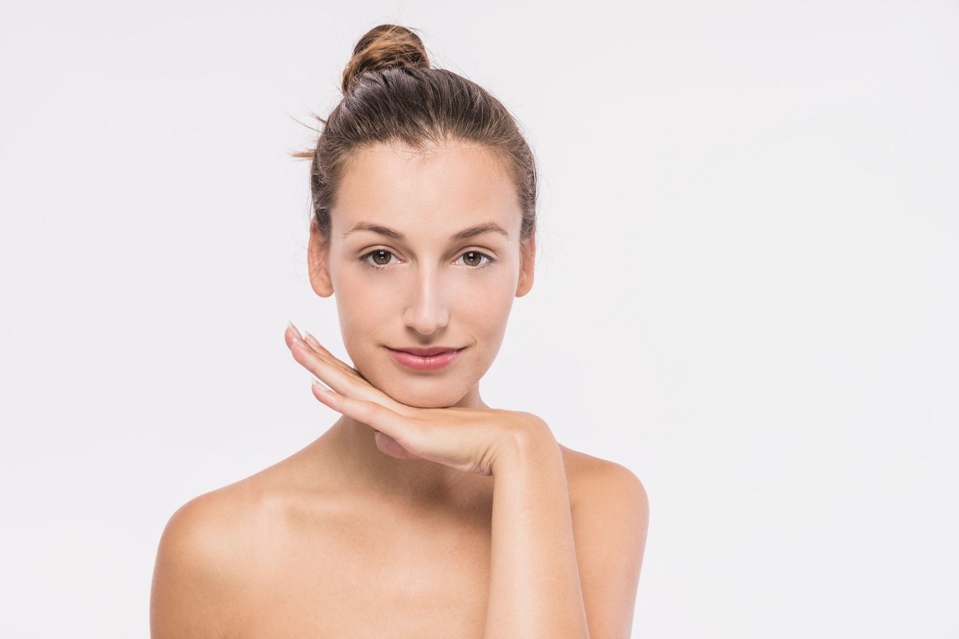 A woman is touching her face with her hand and smiling.