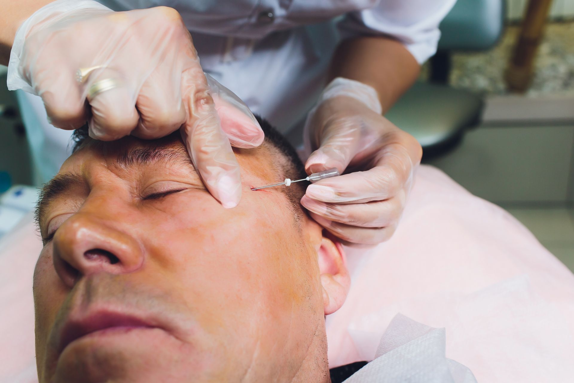 A man is getting a botox injection in his forehead.