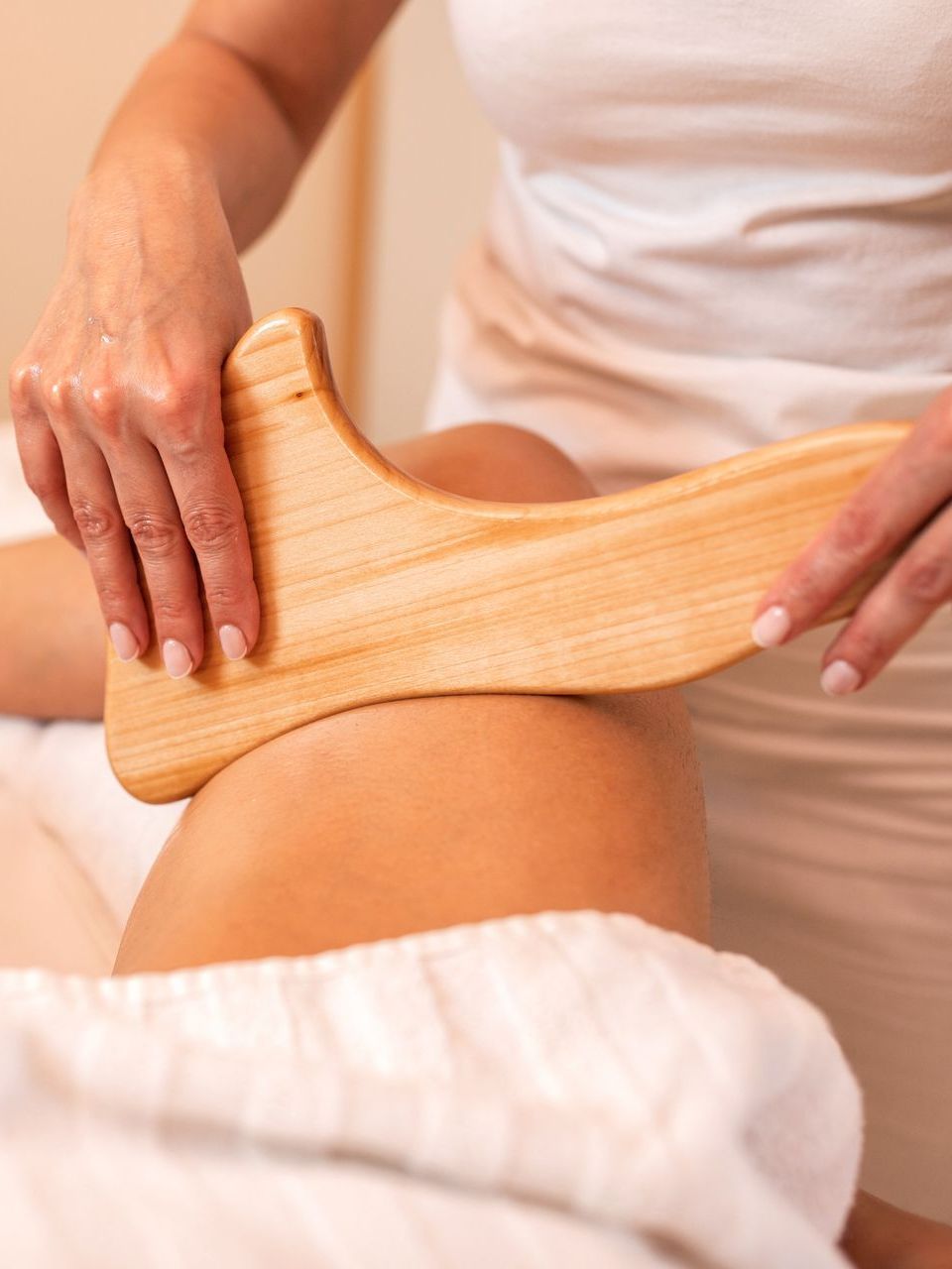 A woman is getting a wooden massage on her leg.