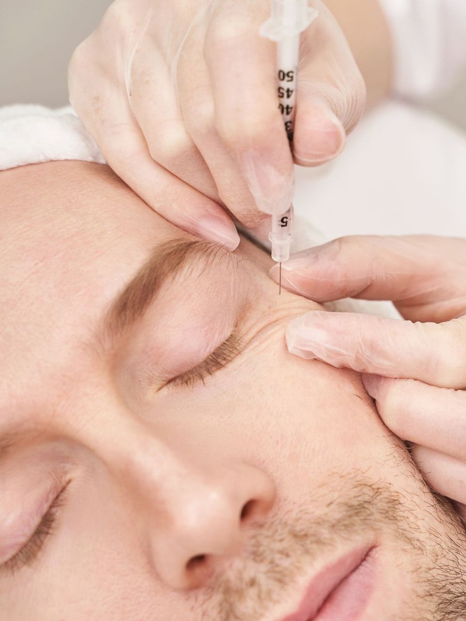 A man is getting a botox injection in his eye.
