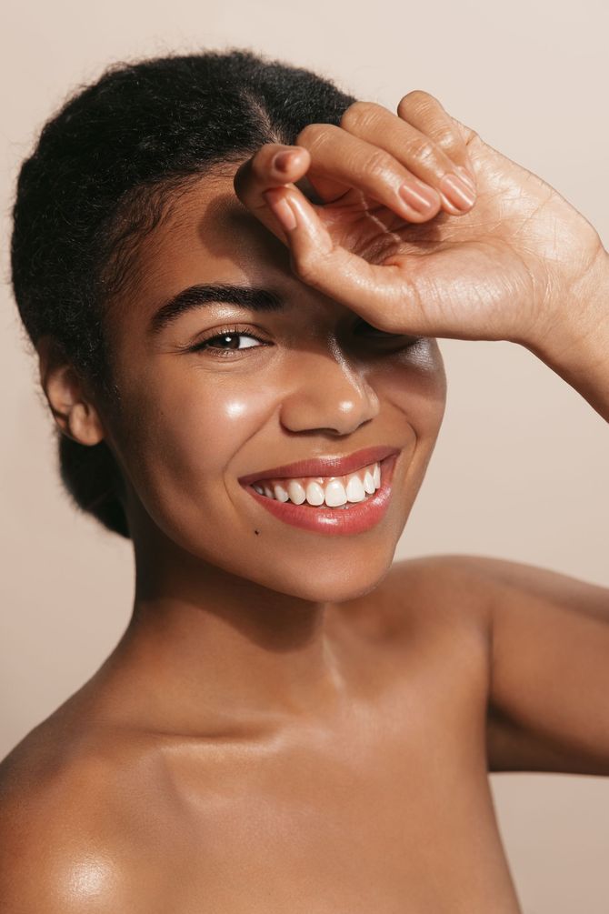 A woman is smiling and covering her face with her hand.