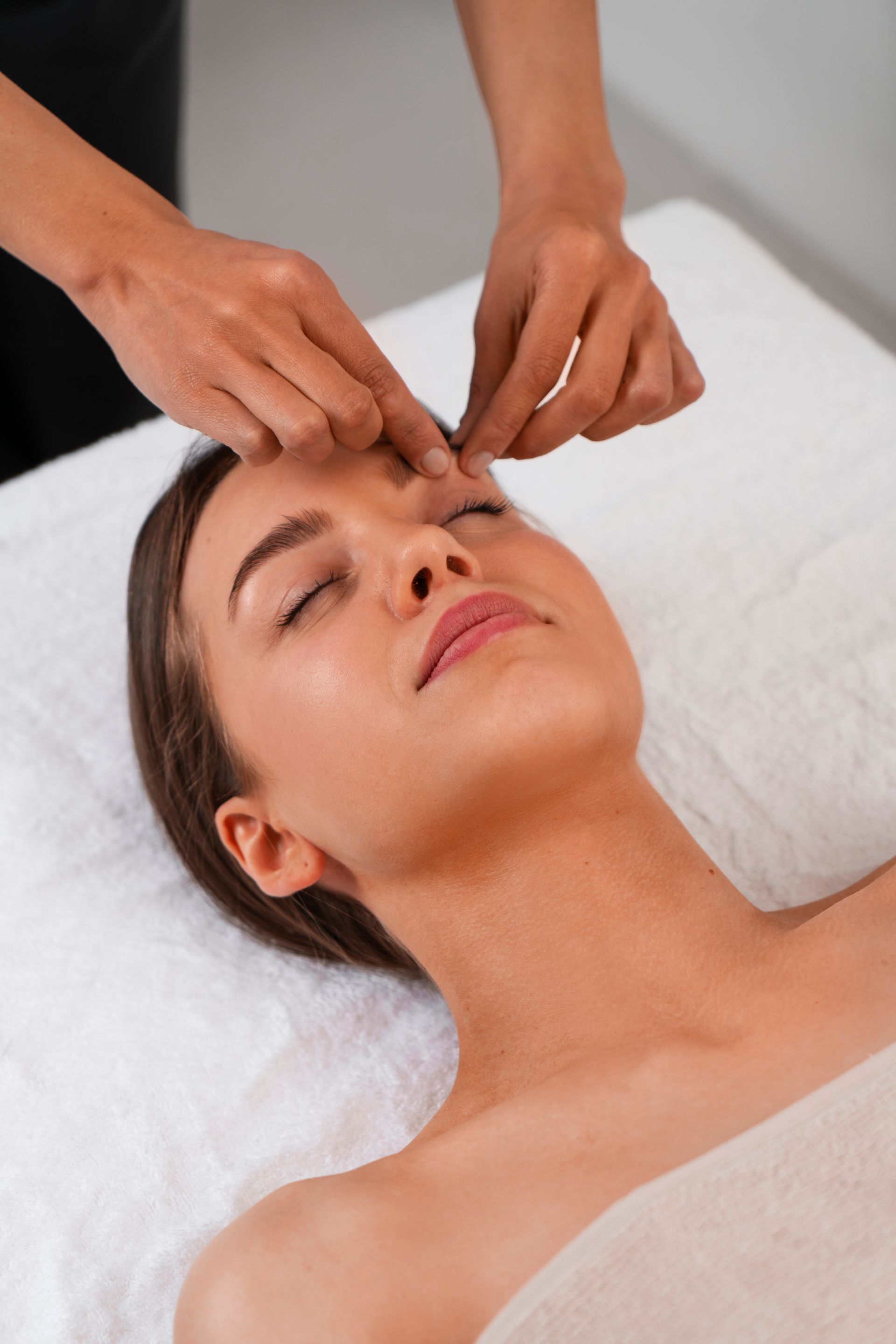 A woman is getting a face massage at a spa.