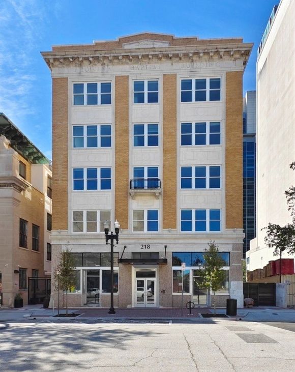 Four-story building with tan and white facade, large windows, and a classic design.