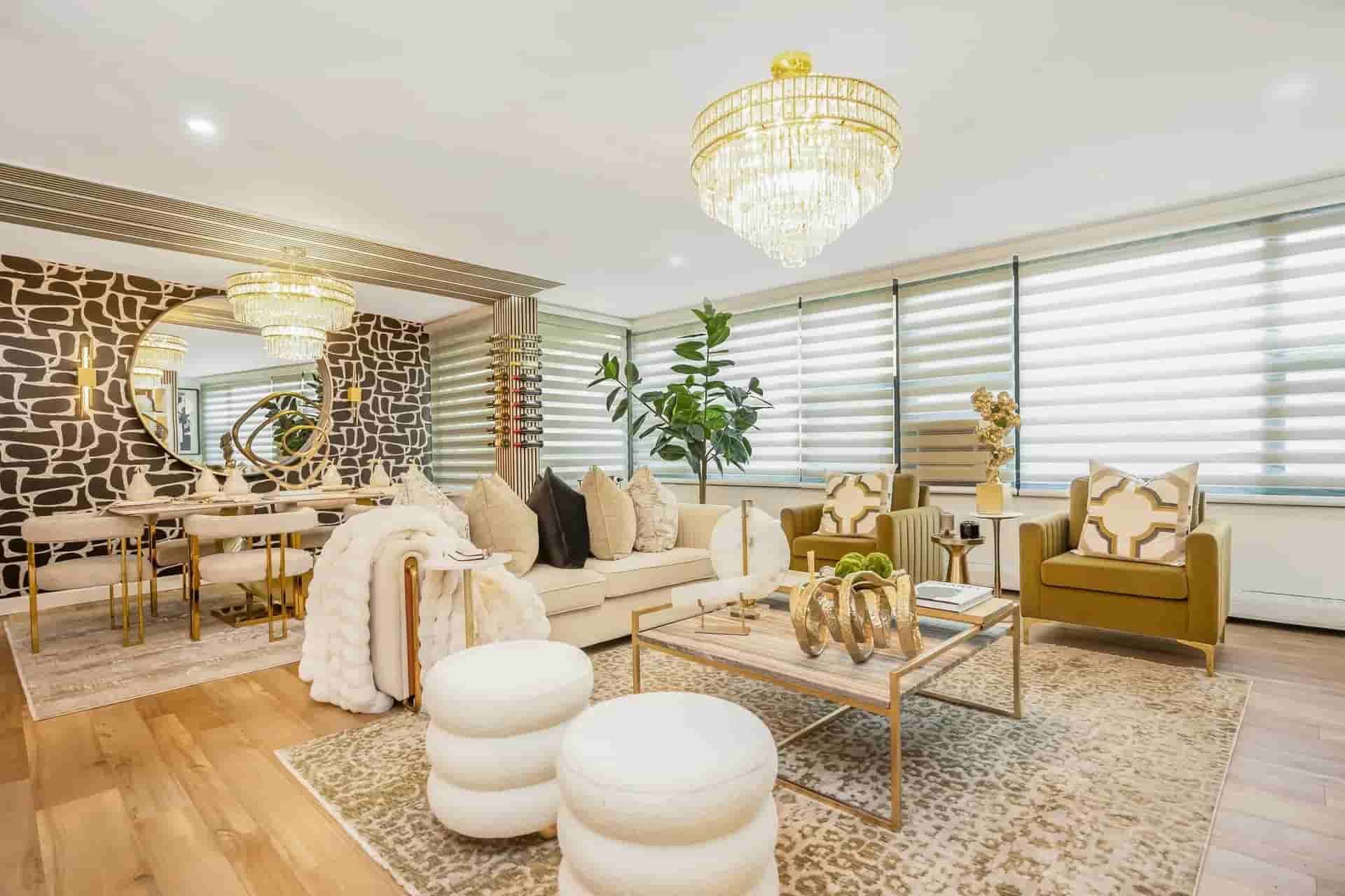 Elegant living room with gold decor, chandelier, patterned rug, mirrored wall, and modern seating