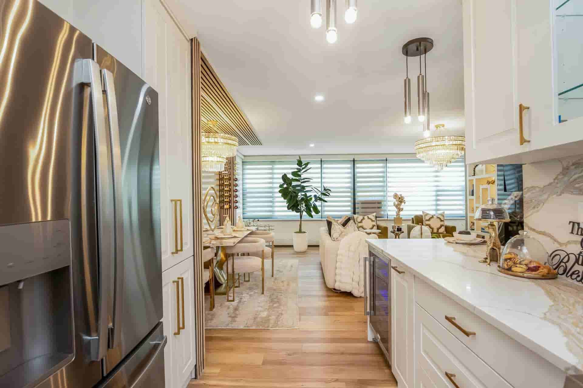 Bright modern kitchen with white cabinets, stainless fridge, island, and dining area by a window