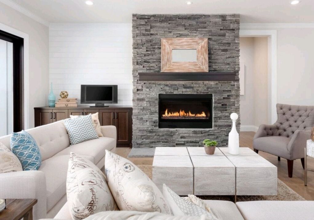 Modern living room with stone fireplace, neutral sectional sofa, armchair, and TV console