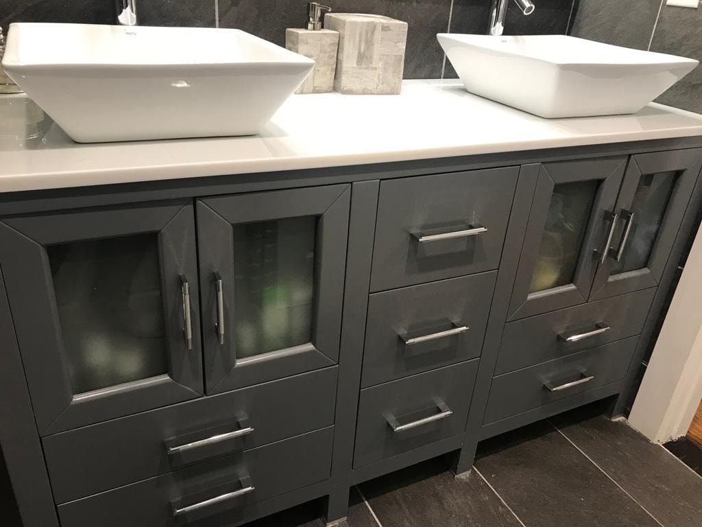 Double-sink dark vanity with drawers and cabinets beneath a white countertop in a bathroom