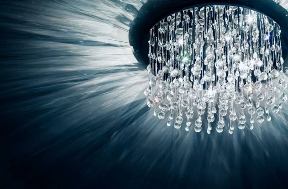 Crystal chandelier casting radiant light and shadows on a dark wall