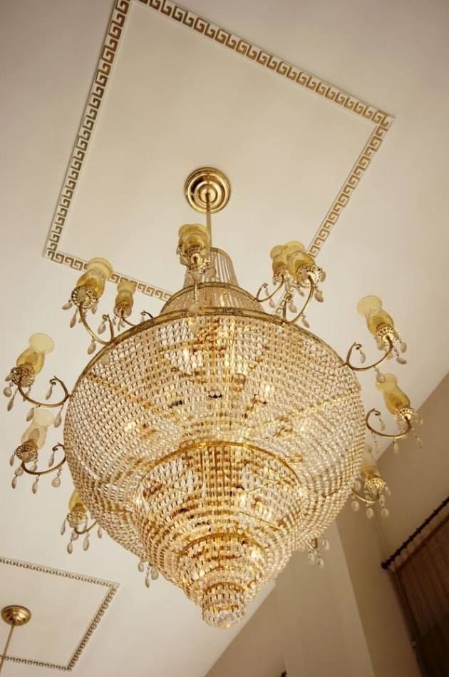 Ornate gold crystal chandelier hanging from a white ceiling in an elegant room