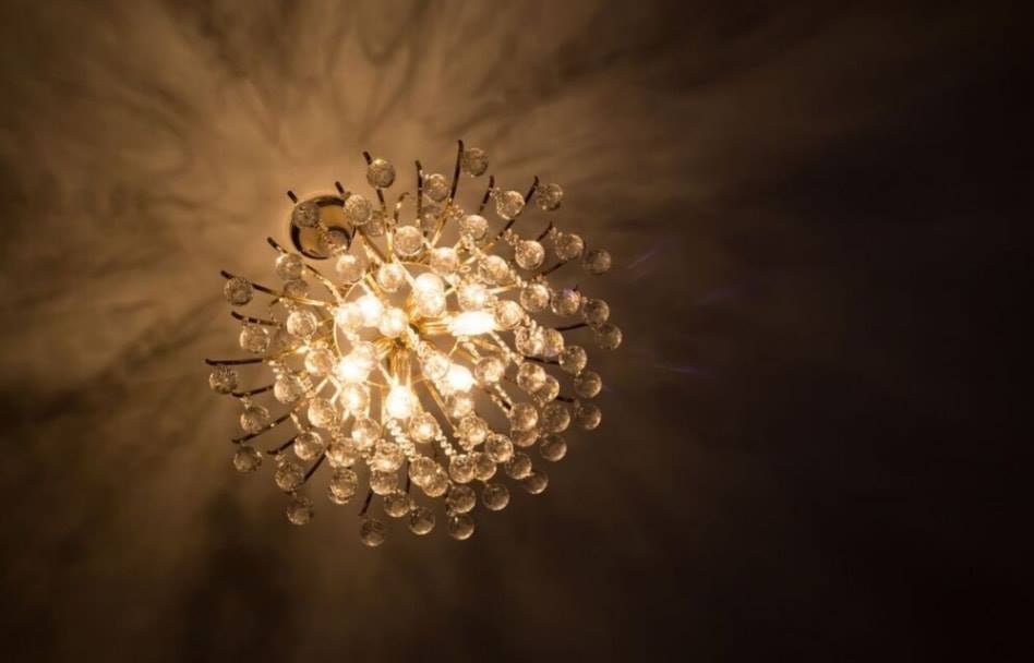 Close-up of a glowing crystal chandelier casting warm light on a ceiling