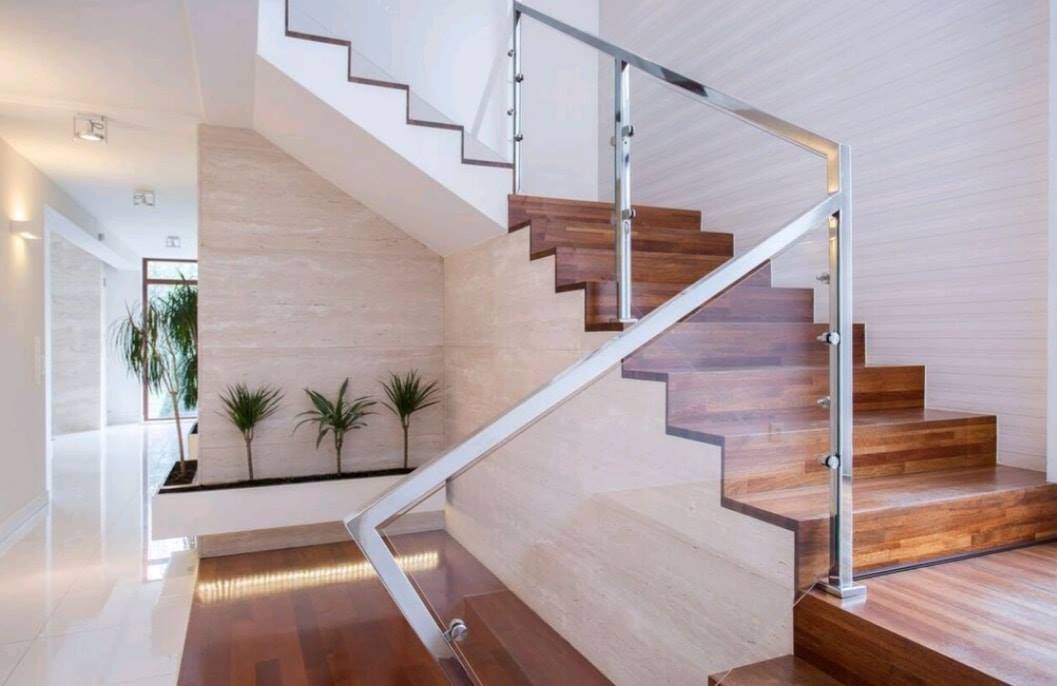 Modern indoor staircase with wooden steps, glass railing, and white walls in a bright hallway