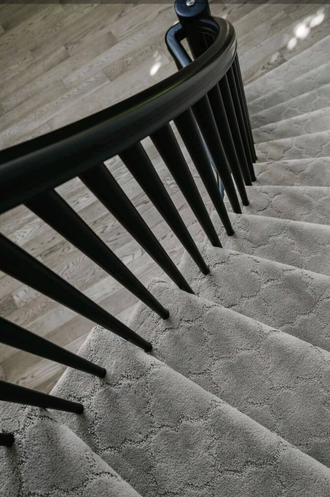 Curved staircase with gray carpet and black metal railing, viewed from above