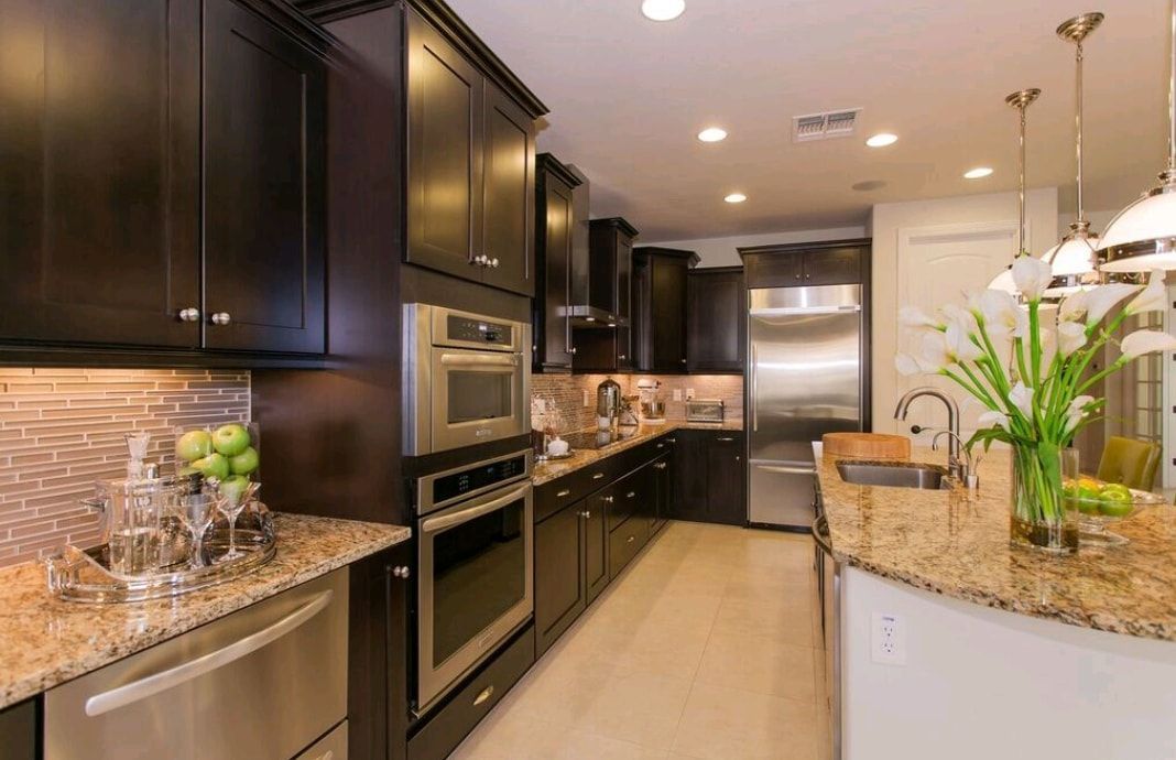 Modern kitchen with dark cabinets, granite countertops, stainless appliances, and a curved island with flowers.