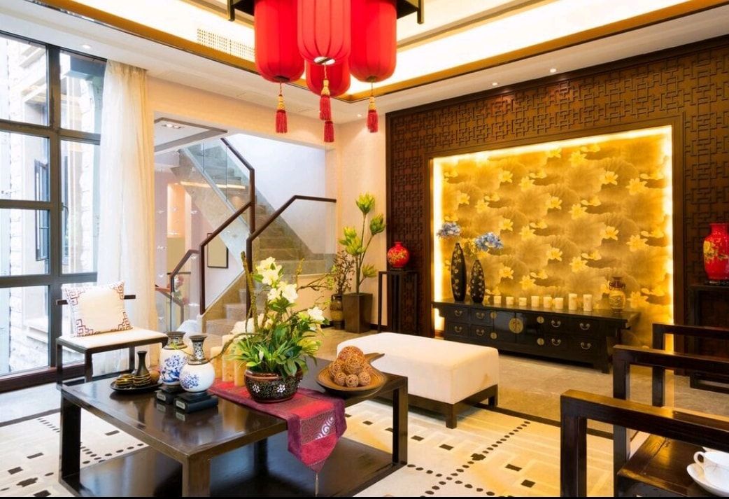 Bright living room with red lanterns, black tables, white seating, and a gold-lit wall panel