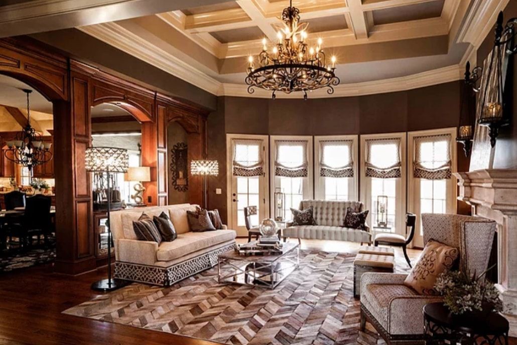 Elegant living room with chandeliers, tall windows, patterned wood floor, and ornate sofas