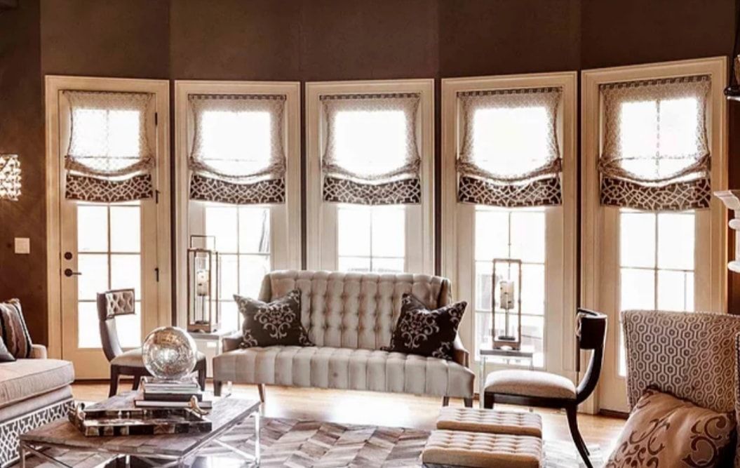 Elegant living room with large windows, patterned sofas, and warm neutral decor