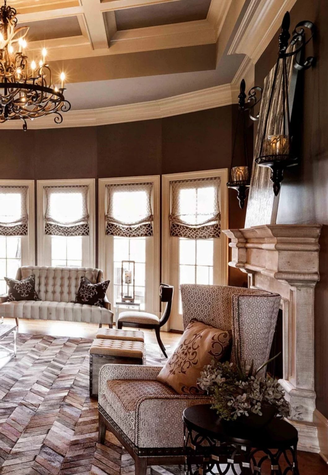 Elegant living room with tall windows, fireplace, patterned chairs, and a chandelier