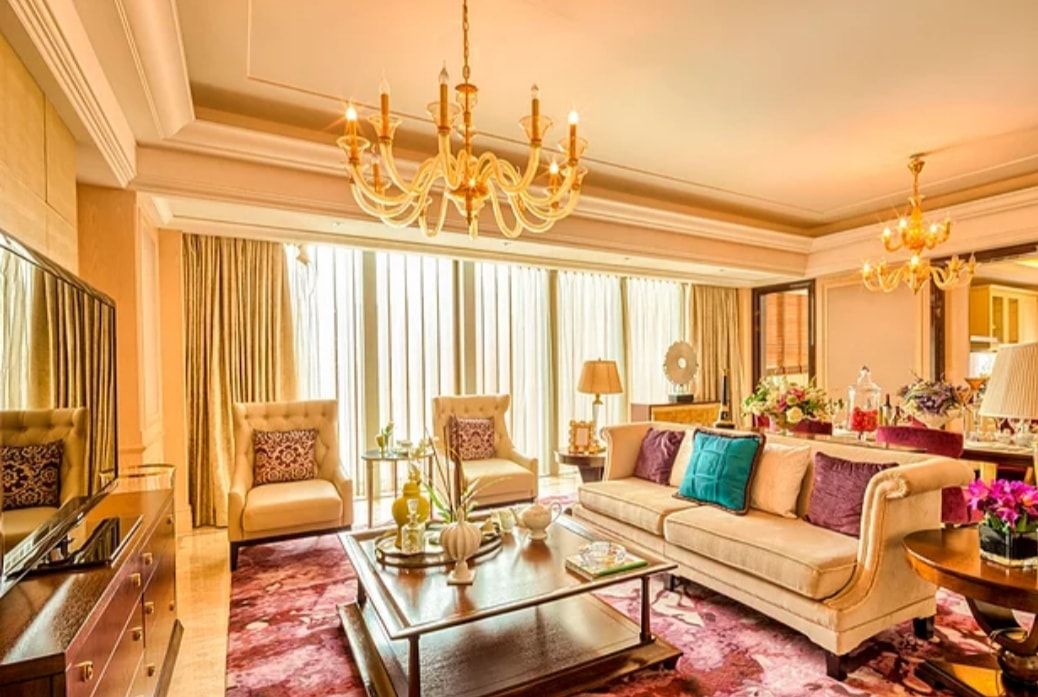 Elegant living room with gold decor, cream sofa, chandelier, and large bright windows