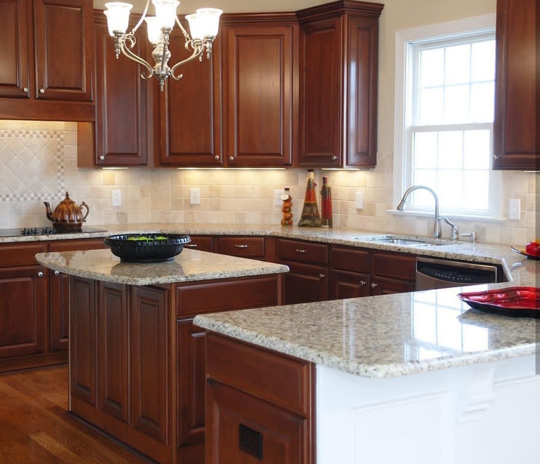 Bright kitchen with dark wood cabinets, granite countertops, white island, and window over sink