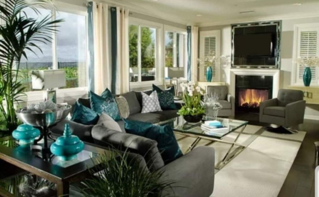 Bright luxury living room with teal accents, fireplace, large windows, and a sectional sofa
