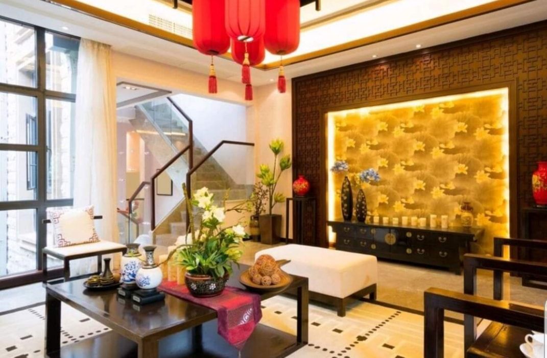 Elegant living room with red lanterns, black furniture, and a gold accent wall with backlit panel