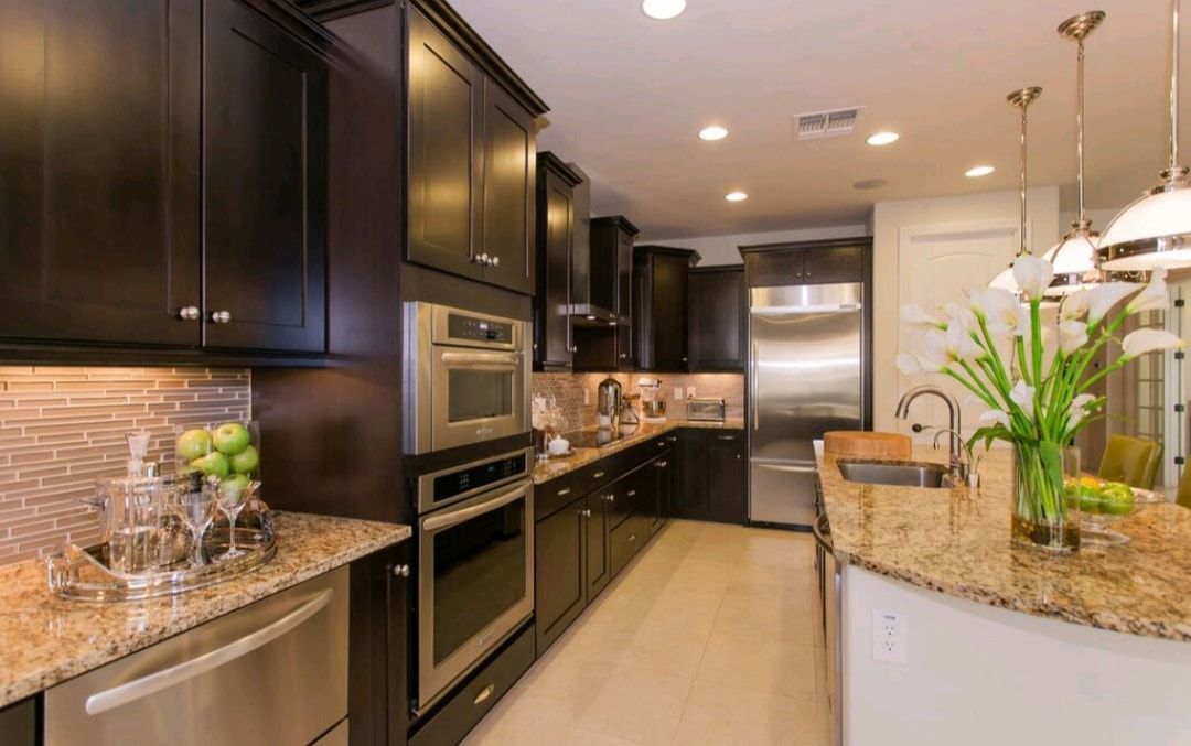 Modern kitchen with dark cabinets, granite countertops, stainless appliances, and a tiled backsplash
