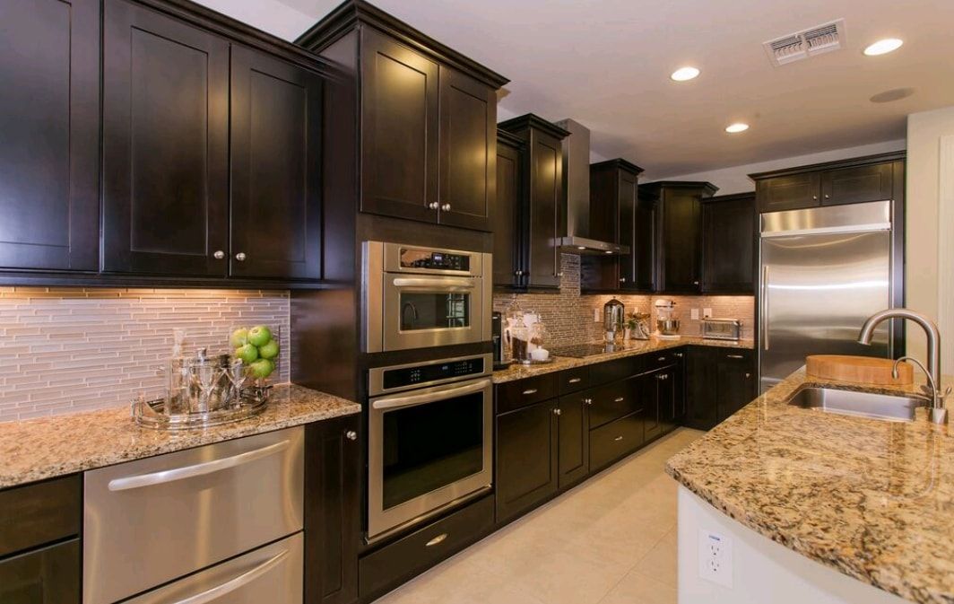 Modern kitchen with dark cabinets, stainless appliances, and granite countertops