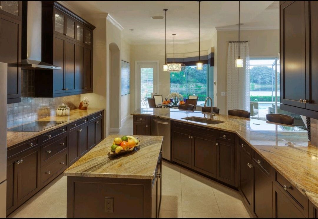 Spacious modern kitchen with dark cabinets, granite island, and large windows overlooking a yard.