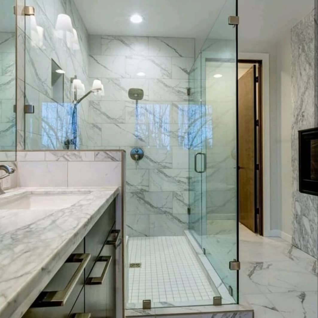Modern marble bathroom with a glass-enclosed shower and double vanity, in white and gray tones