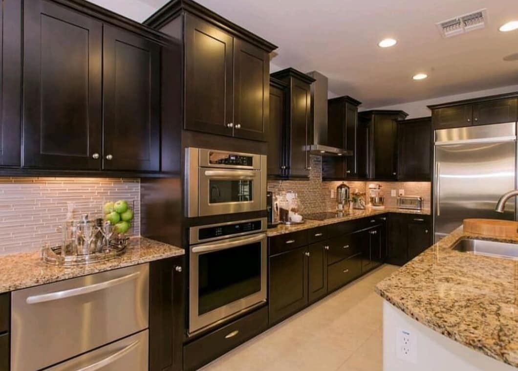 Modern kitchen with dark cabinets, granite countertops, and stainless steel appliances