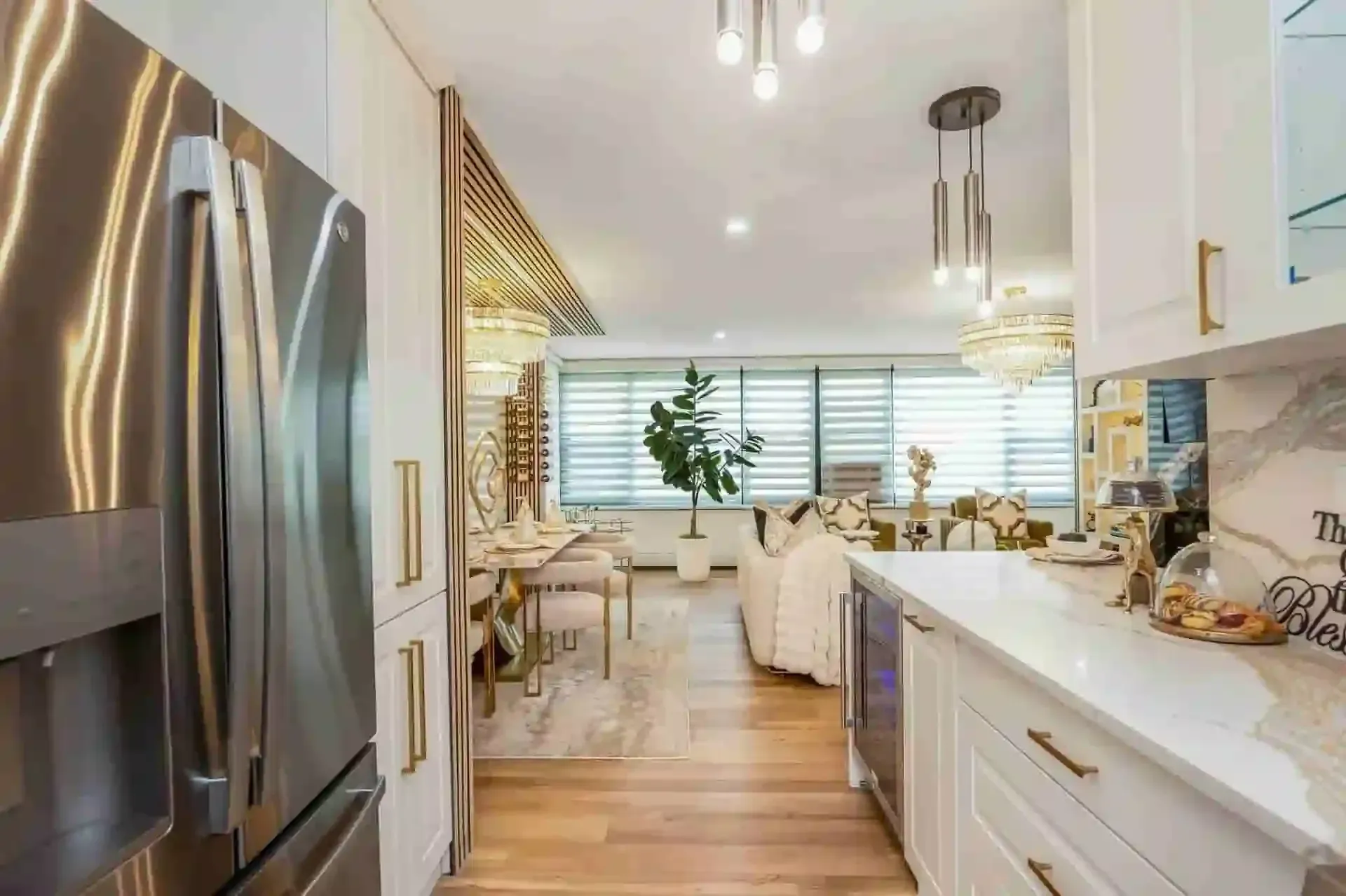 Bright modern kitchen with white cabinets, stainless fridge, wood floors, dining area by the window