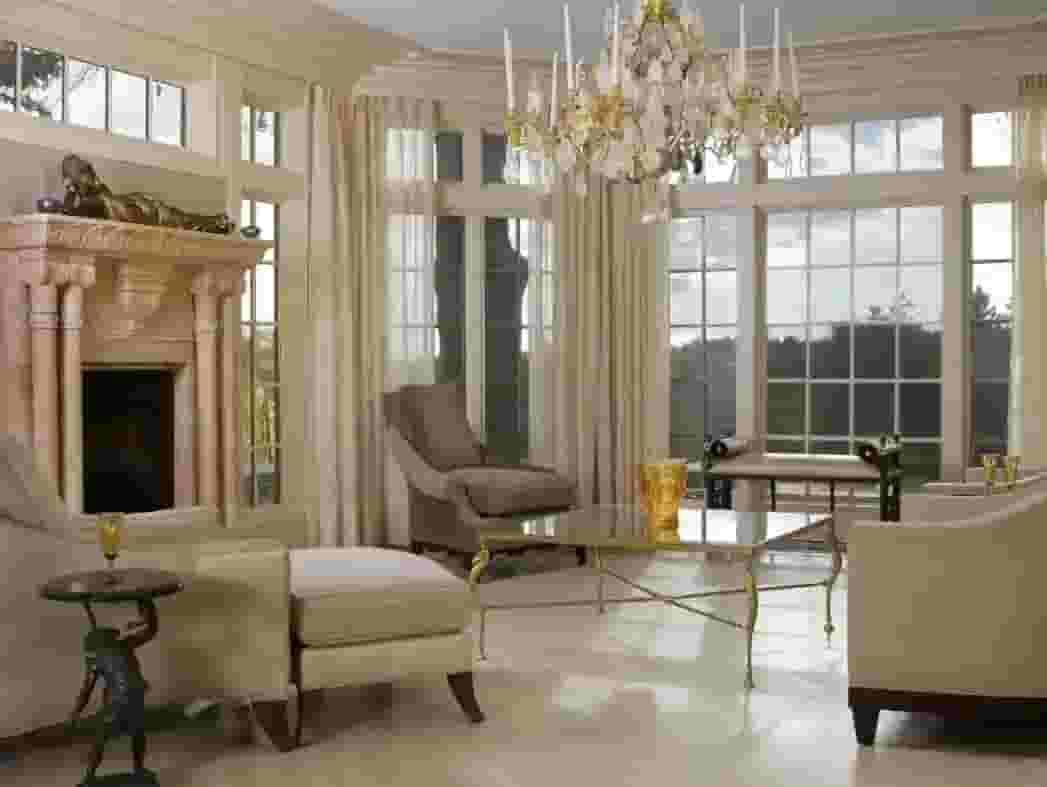 Elegant living room with large windows, chandelier, fireplace, and cream-colored seating