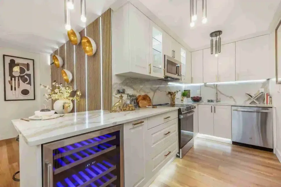 Bright modern kitchen with white cabinets, marble island, and blue-lit wine cooler