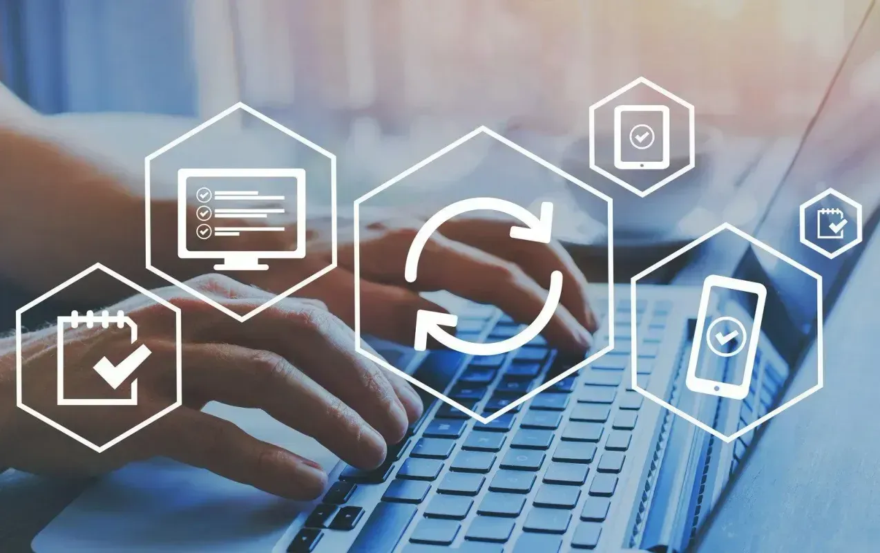 Hands typing on a laptop with digital interface icons overlaid in a blue-toned office setting