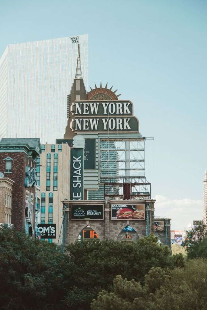Las Vegas strip signs, including “New York New York,” above trees and buildings at dusk