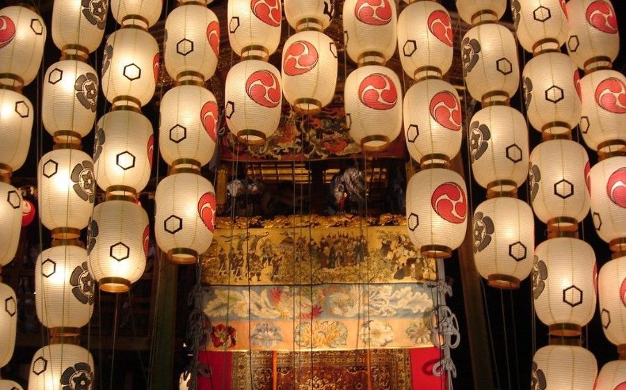 Rows of white and red festival lanterns hanging around a decorated float or shrine stage