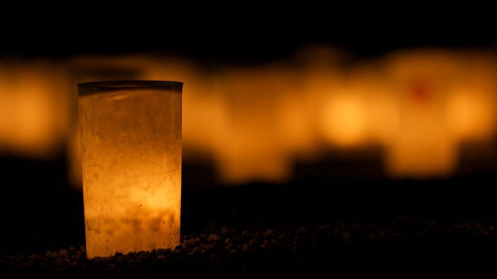 Glowing paper lantern on the ground at dusk, with blurred warm lights in the background