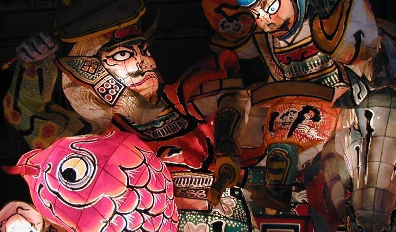 Colorful illustrated lanterns with stylized faces and a bright pink fish in a festive display