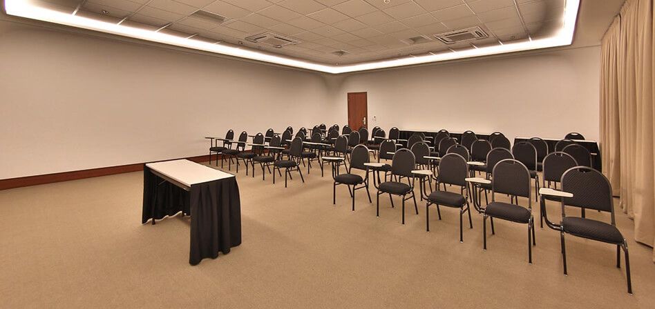 Uma sala de conferências com fileiras de cadeiras e uma mesa