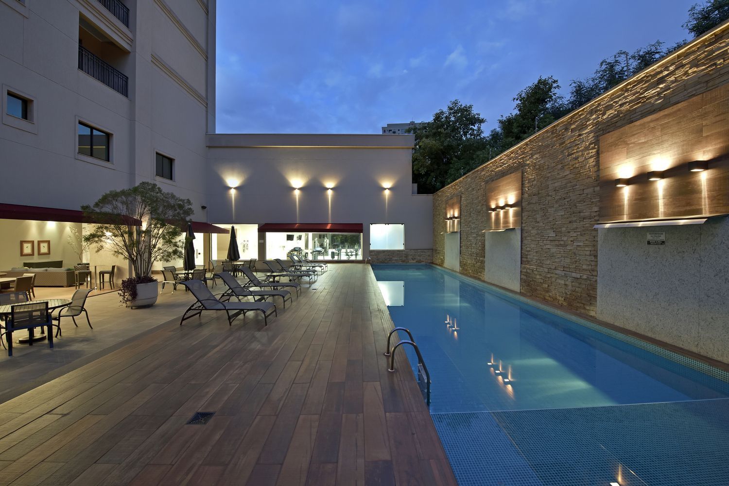 Uma grande piscina é cercada por um edifício à noite