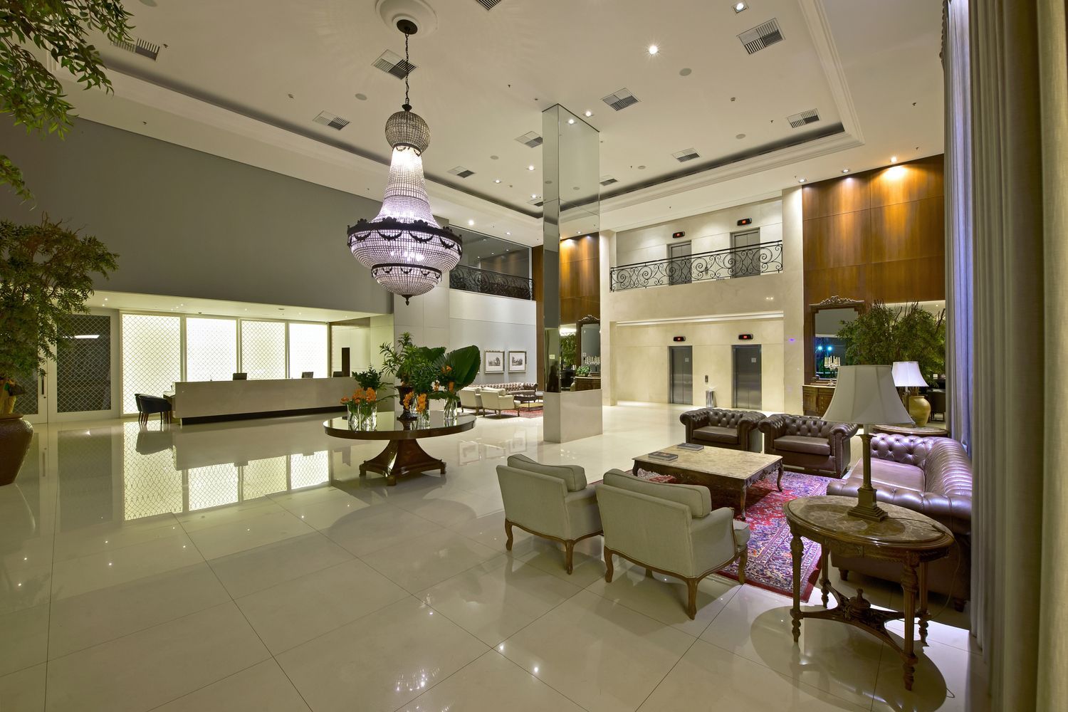 Um lobby com um sofá, cadeiras, pufe e mesas.